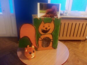 Zdjęcie wiewiórki oraz karton na którym namalowano wiewiórkę z dziurką na brzuszku do wkładania żołędzi