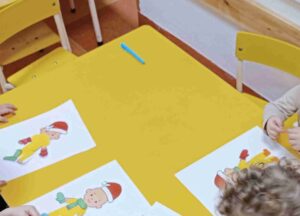 Dzieci przyklejają części garderoby do figurki dziecka z papieru