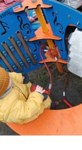 Dziecko siedzi na ławce przed instrumentem muzycznym na placu zabaw