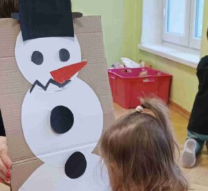 Dzieci wyklejają bałwana z papieru -naklejają gotowe elementy