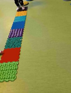 Tor przeszkód ułożony z kolorowych kafli i kostek o różnych fakturach.