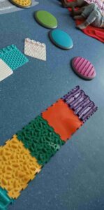 Tor przeszkód ułożony z kolorowych kafli i kostek o różnych fakturach.