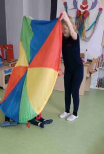 Dziecko chowa się pod kolorową chustą 